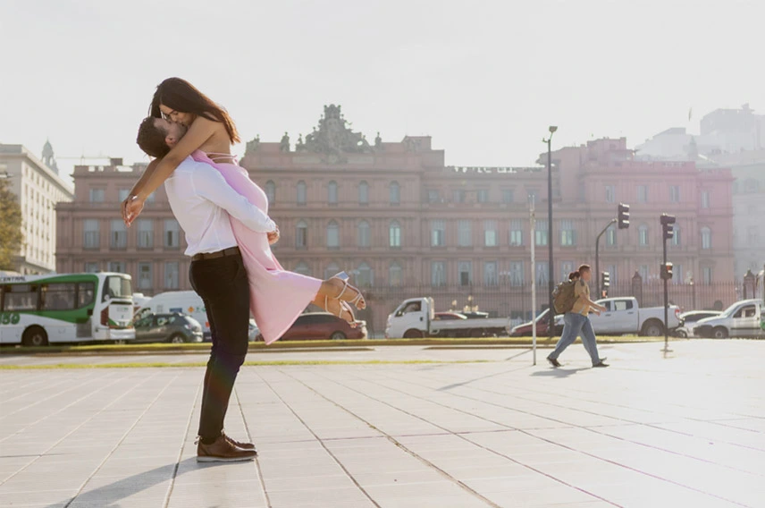 Couple sharing a romantic kiss after a surprise proposal in Buenos Aires with the city skyline in the background